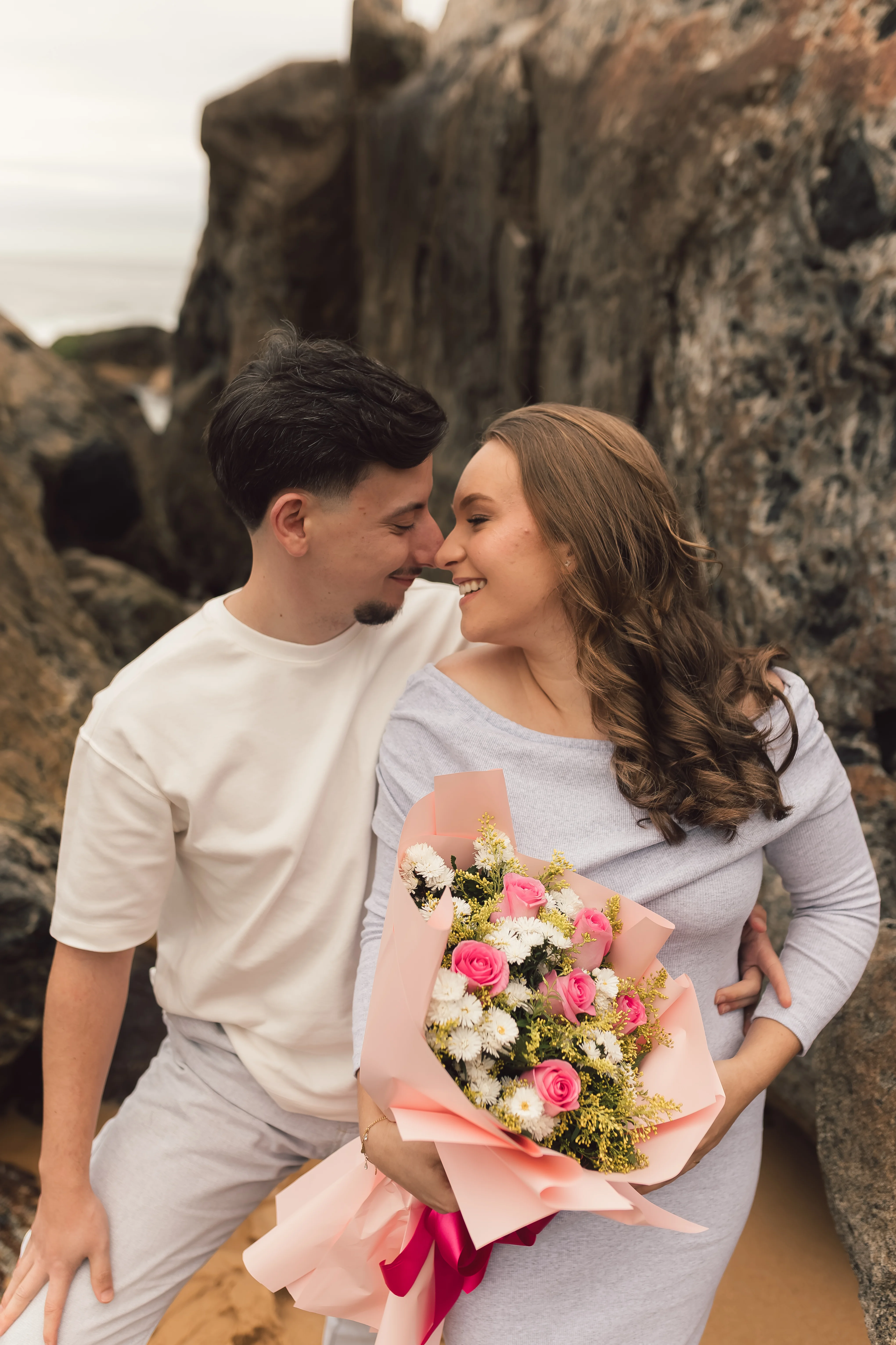 Casal no ensaio revelação com o buquê de rosas cor-de-rosa