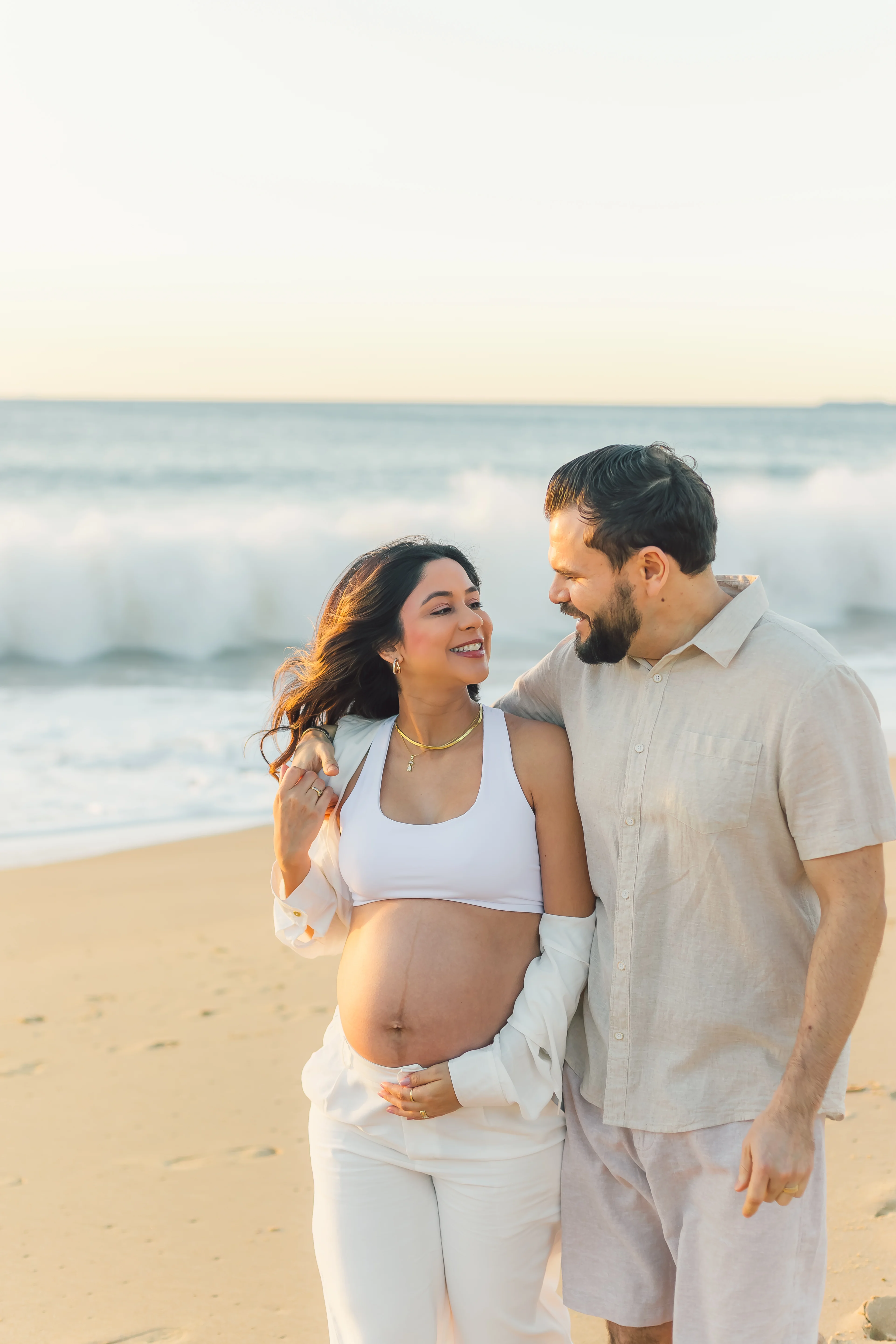 Casal gestante na praia ao pôr do sol