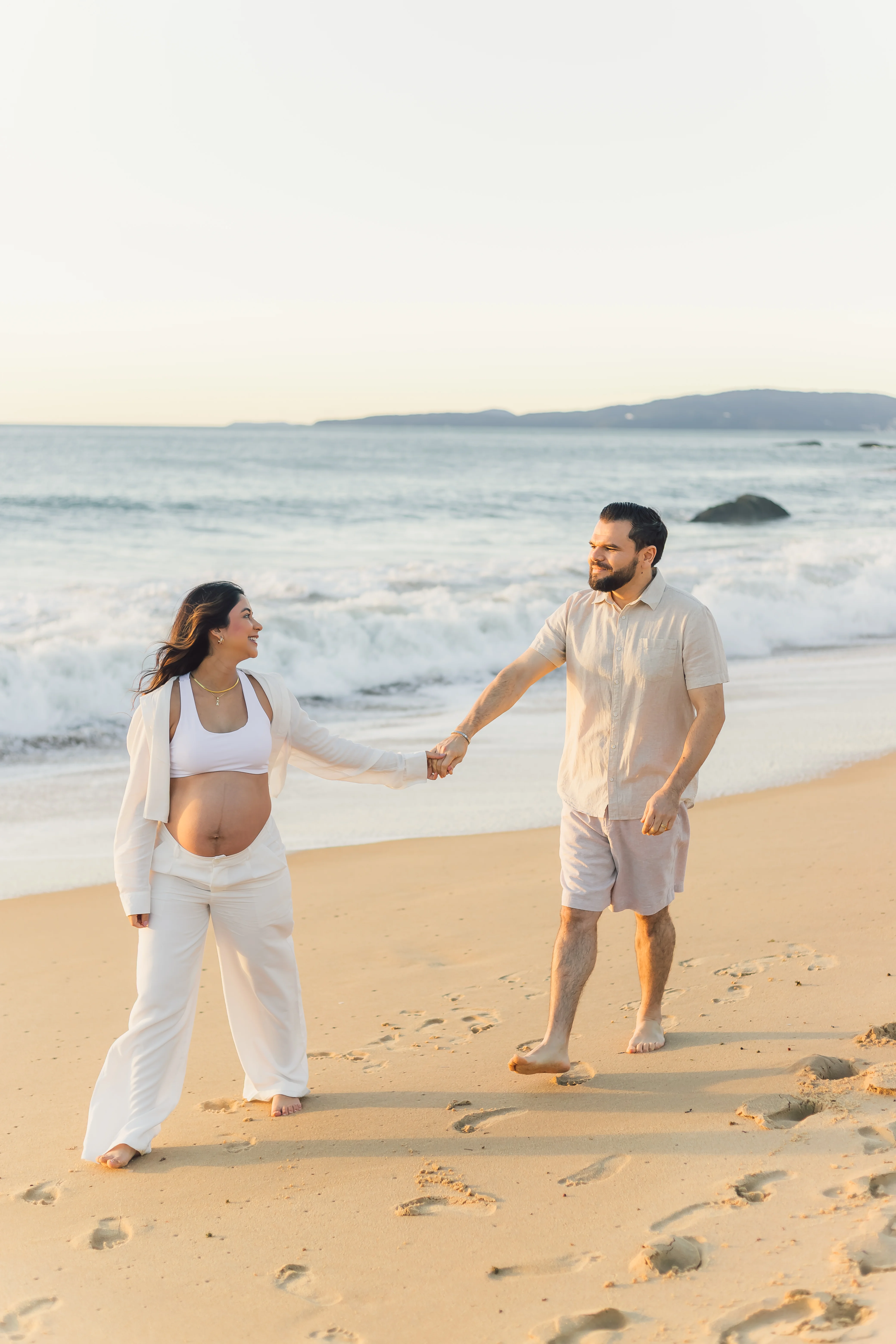Casal gestante de mãos dadas na praia