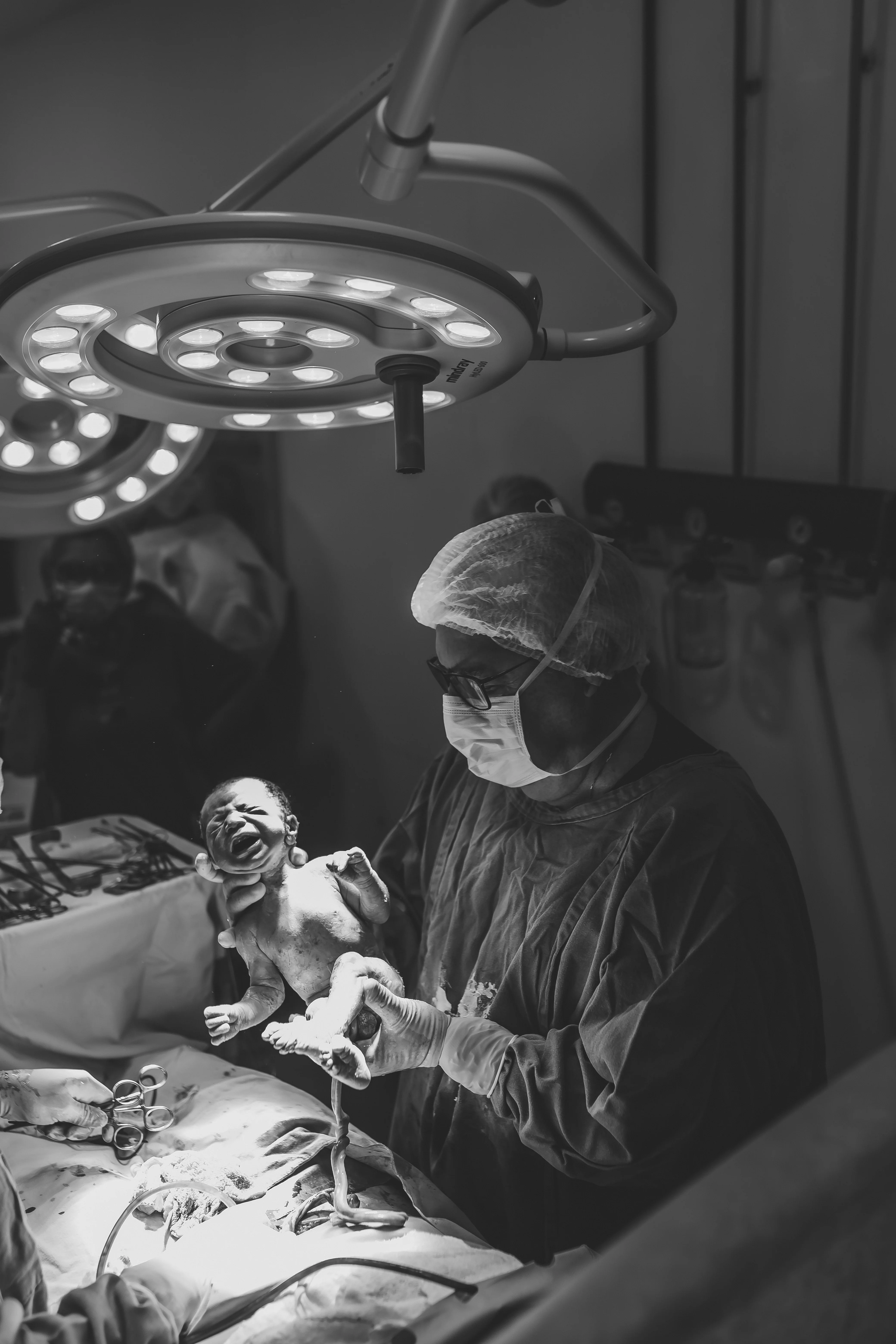 Recém-nascido nas mãos da equipe médica em P&B