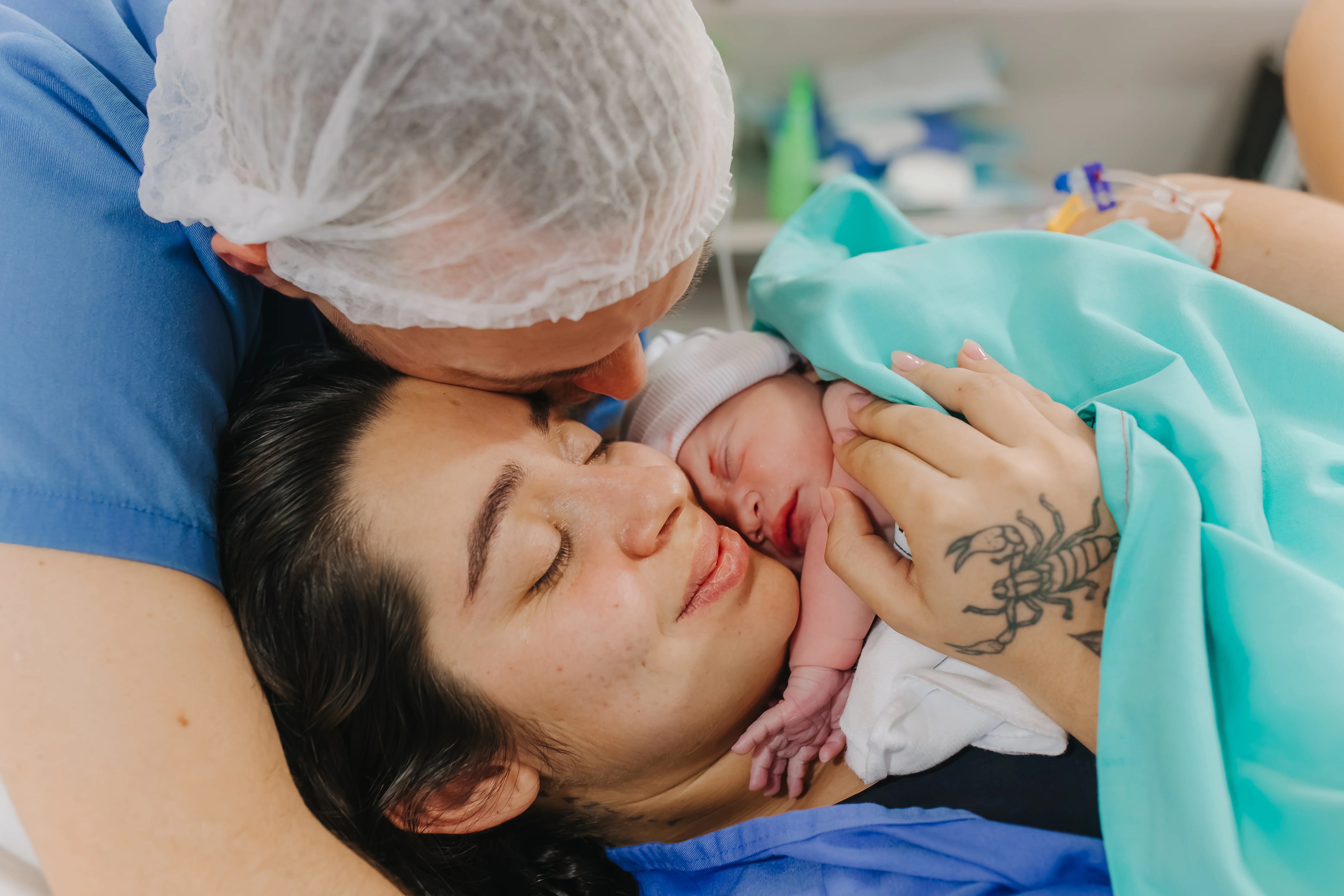 Pai beijando a mãe com o recém-nascido no colo