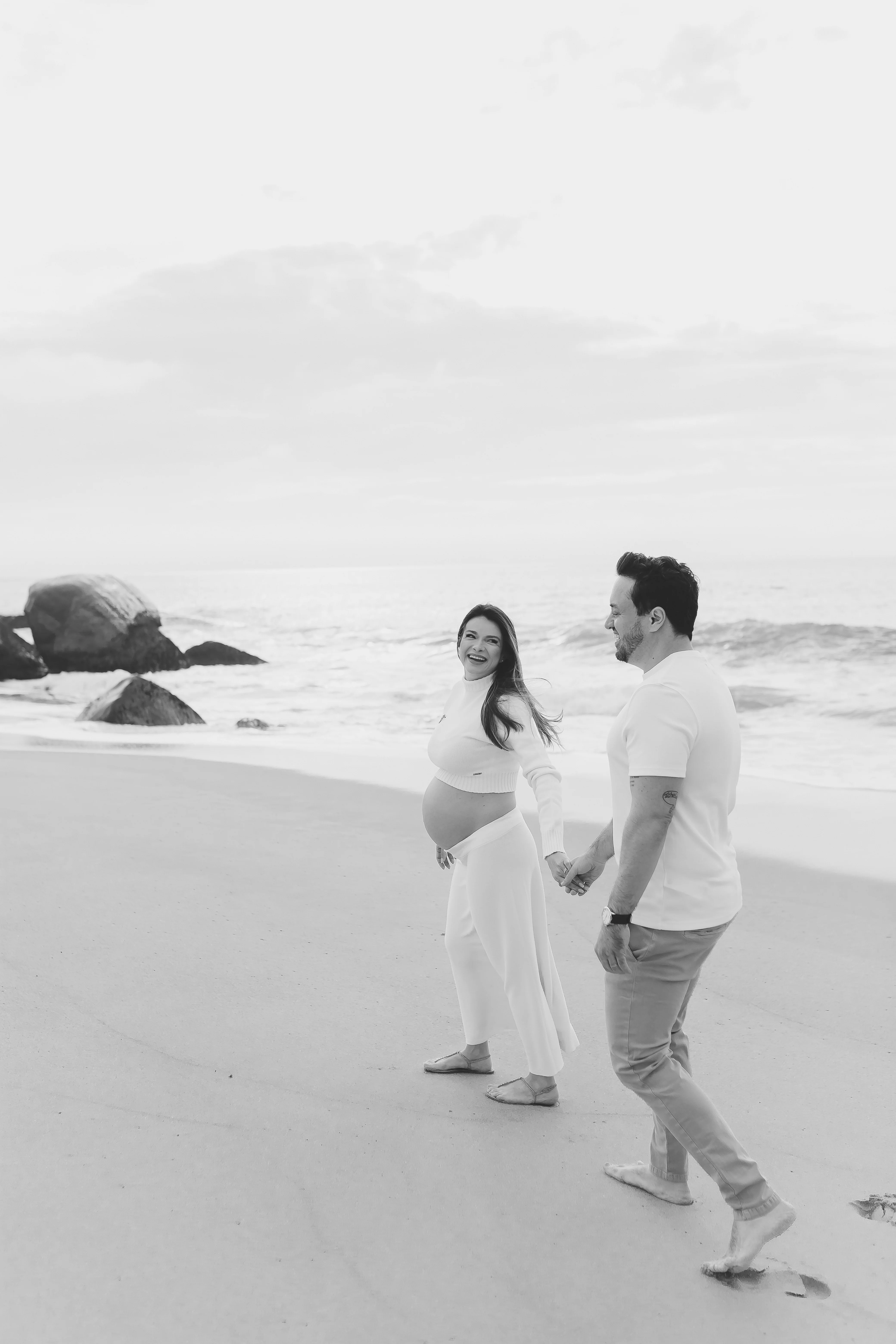 Casal gestante caminhando na areia em P&B