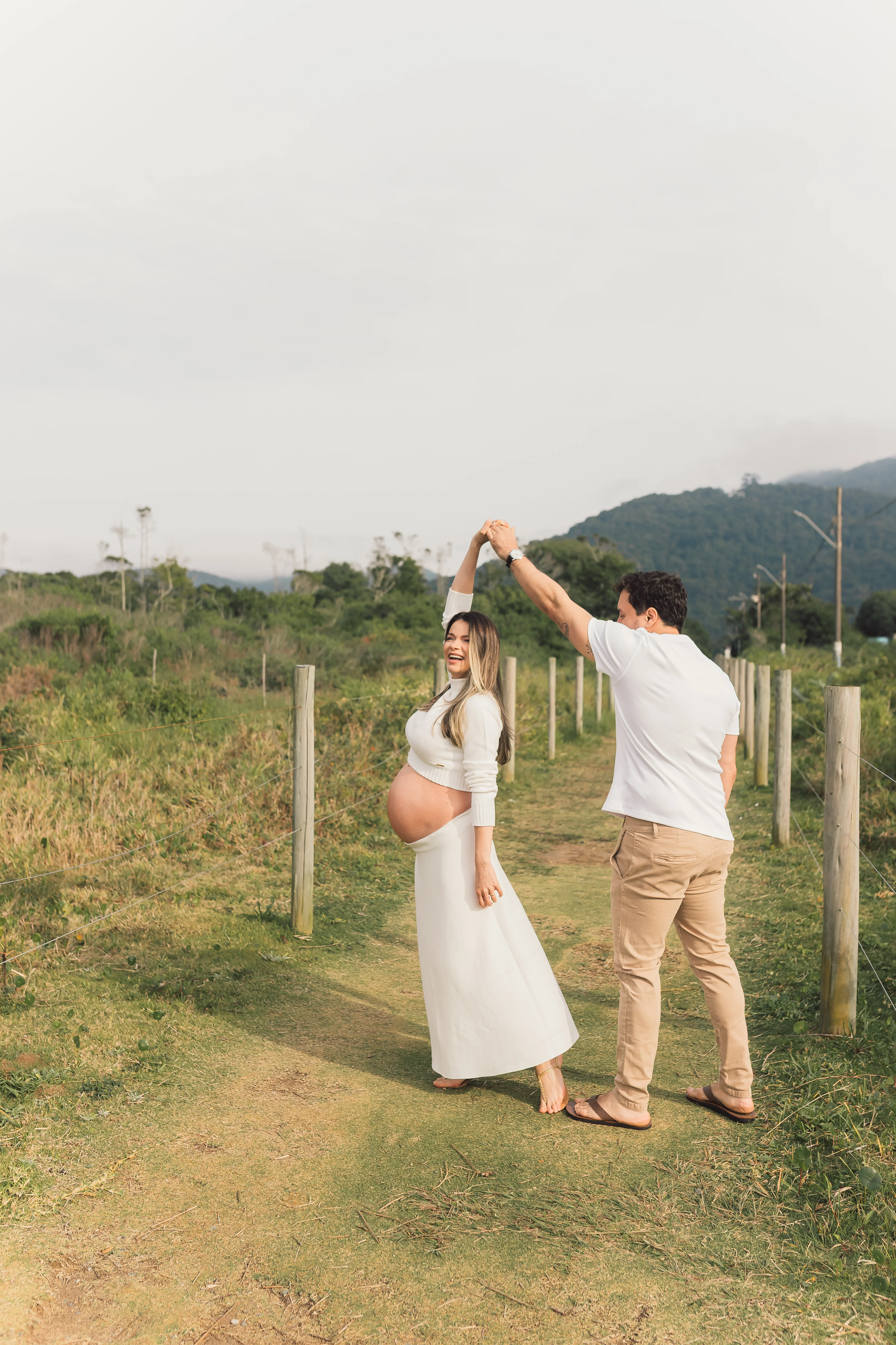 Casal gestante dançando no campo